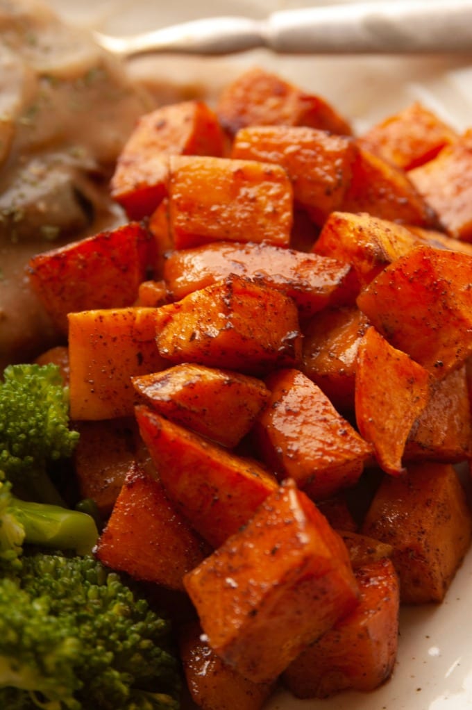 Maple roasted sweet potatoes on a white plate with broccoli.