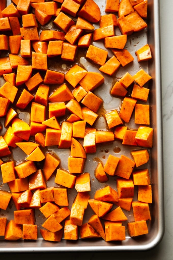 Raw sweet potatoes on a baking sheet.