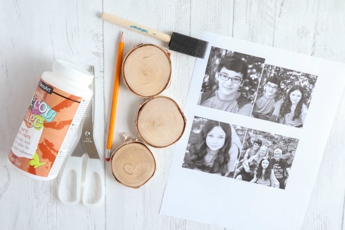 Materials needed to create wood photo ornaments, including wood slices, photographs, scissors, etc.