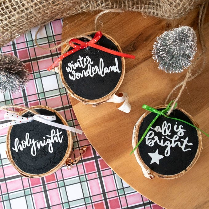Top down view of three Christmas ornaments with holiday sayings cut out of vinyl.