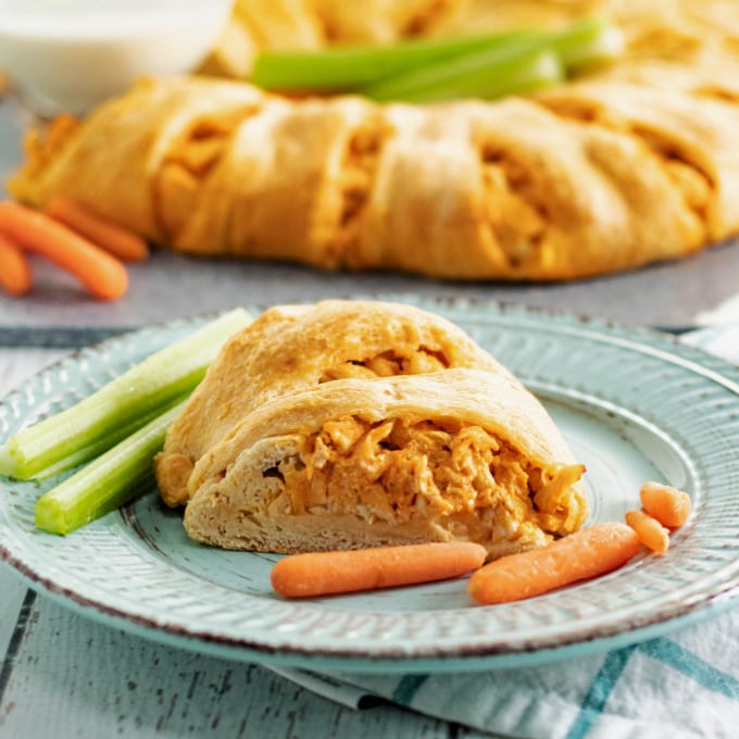 A piece of buffalo chicken appetizer on a plate with carrots and celery.
