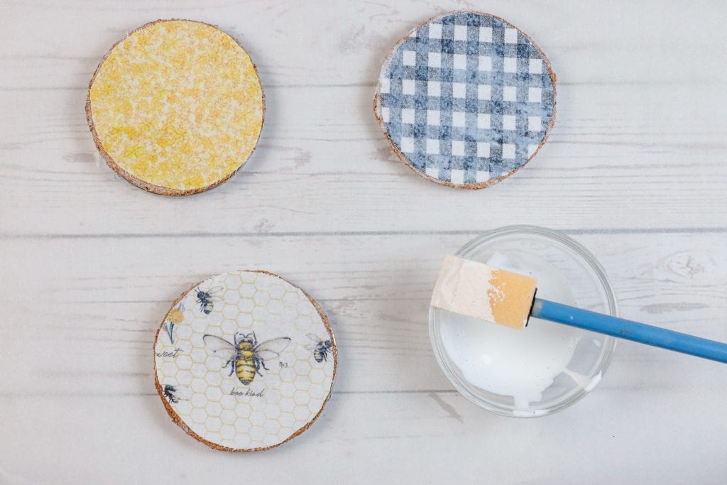 Mason Jar Lid Coasters DIY project:
step by step instructions for making Mason Jar Lid Coasters with mason jar lids, mod podge, paint, fabric, and cork.