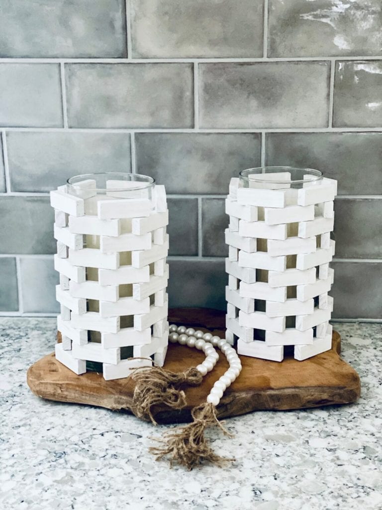 Close up image of candle holders made from old Jenga pieces atop a wood slice.