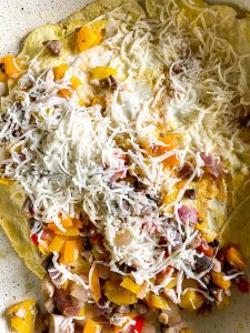 How to Make egg quesadillas: Flip and top with the veggies and the rest of the cheese.
