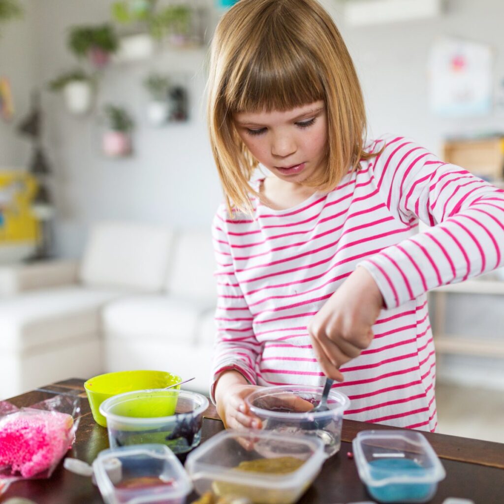 Child mixing slime in small bowls.