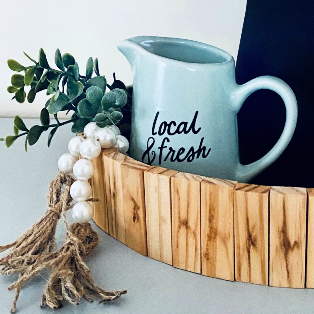 close up of DIY Wood Tiered Tray made from small wood blocks styled with bead garland, and faux greenery