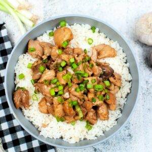 Top down view of Instant Pot bourbon chicken in a bowl next to a black and white towel.