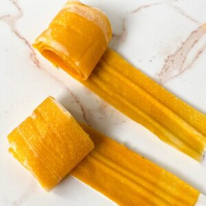 Two rolls of mango fruit leather on a white countertop.