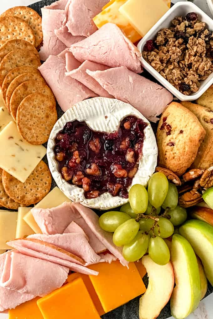 Baked Brie with Cranberry Sauce in the center of a holiday charcuterie tray.