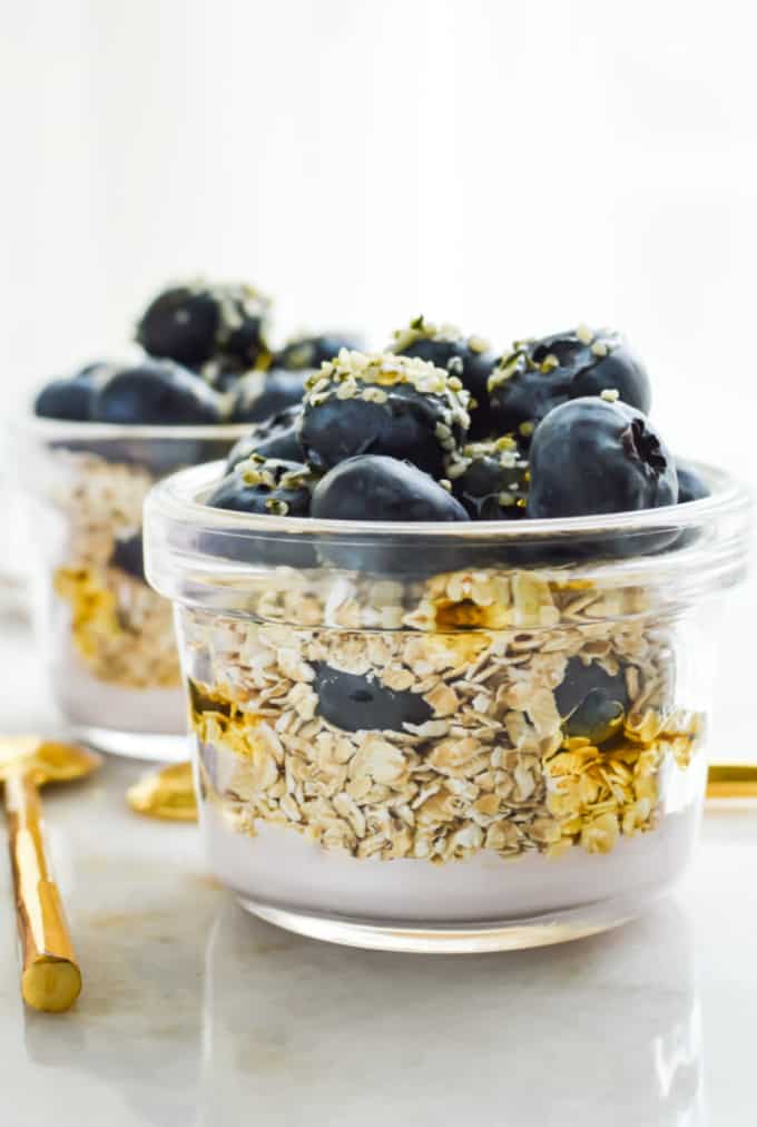 Close up image of two small glass containers filled with blueberry overnight oats.
