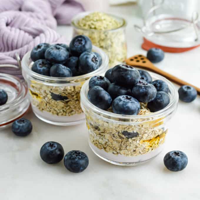 Blueberry overnight oats with yogurt and fresh berries in small jars.