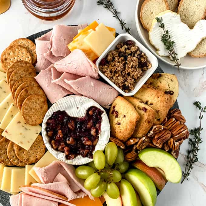 Top down image of a charcuterie board for Thanksgiving, filled with meat, cheese, fruits, nuts, and crackers.