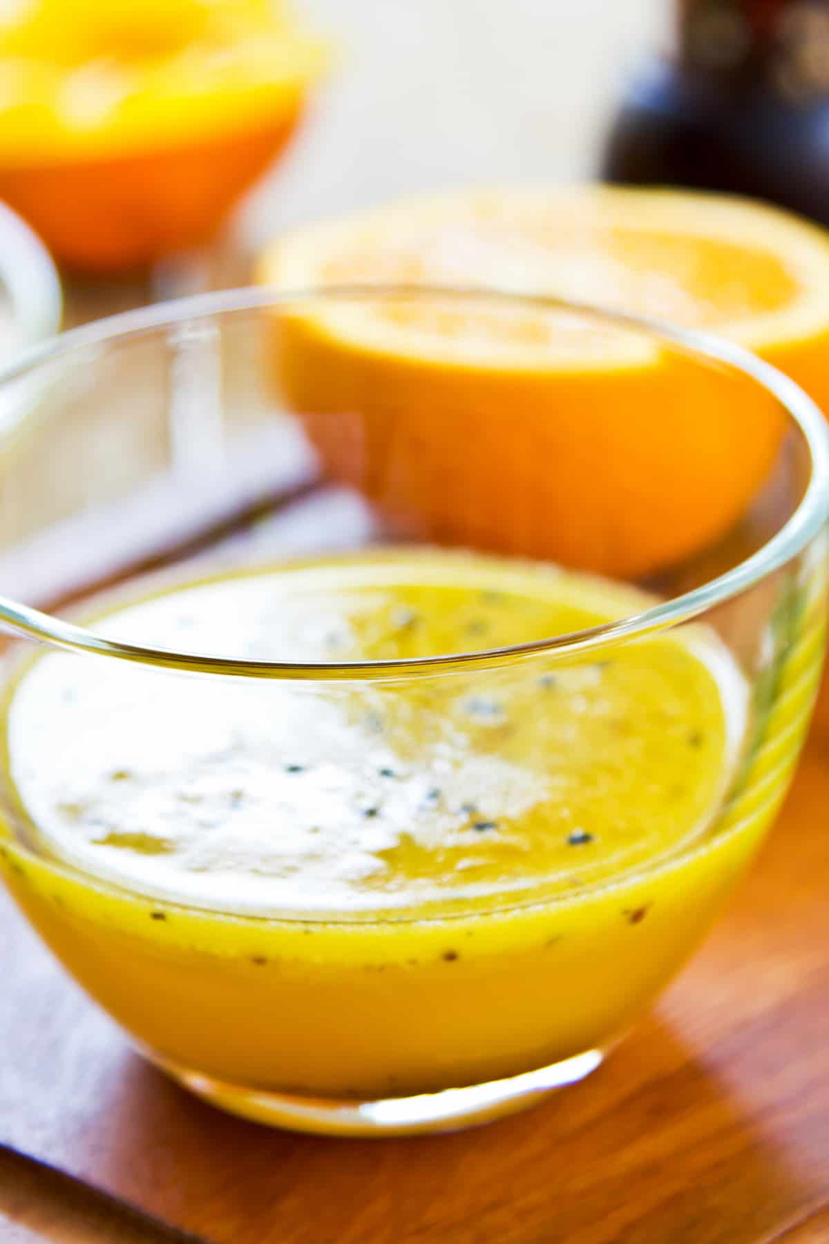 Close up image of orange poppy seed dressing in a glass bowl.