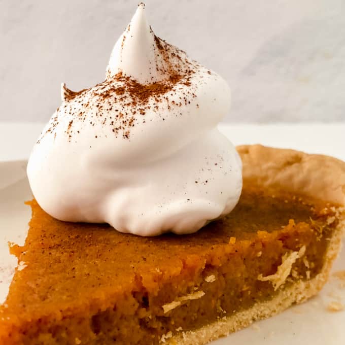Slice of sweet potato pie with a dollop of whippe cream on top.