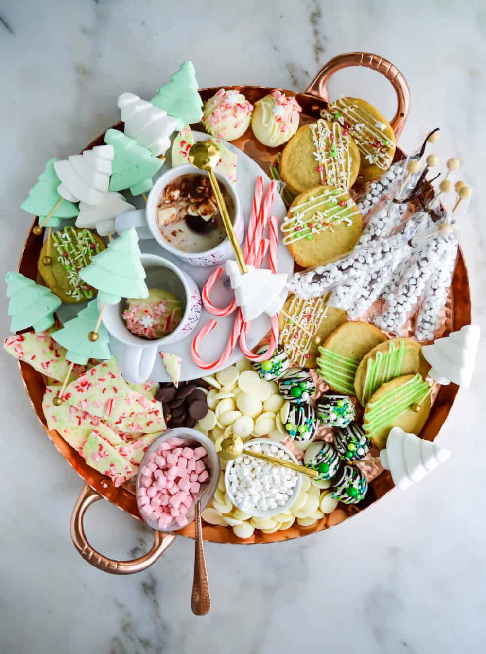 Top down view of a hot chocolate charcuterie board filled with chocolate bark, hot chocolate, marshmallows and cookies.
