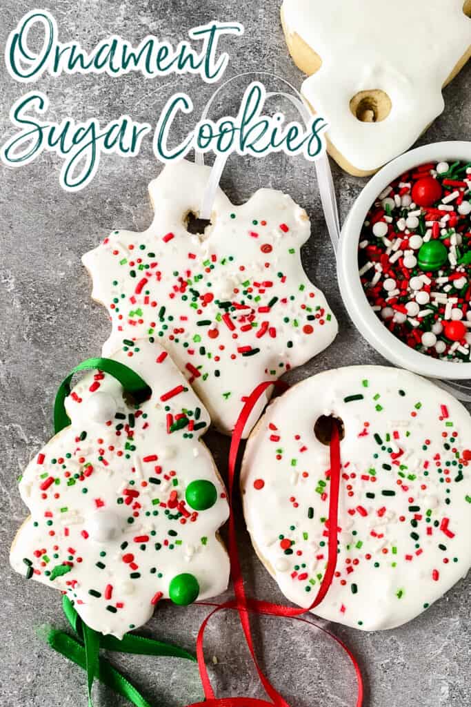 Top down view of ornament sugar cookies with ribbon hangers next to a bowl of sprinkles.