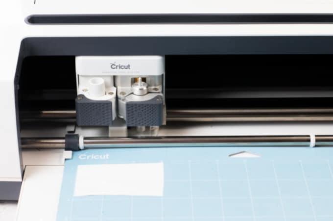A Cricut machine cutting out a word.