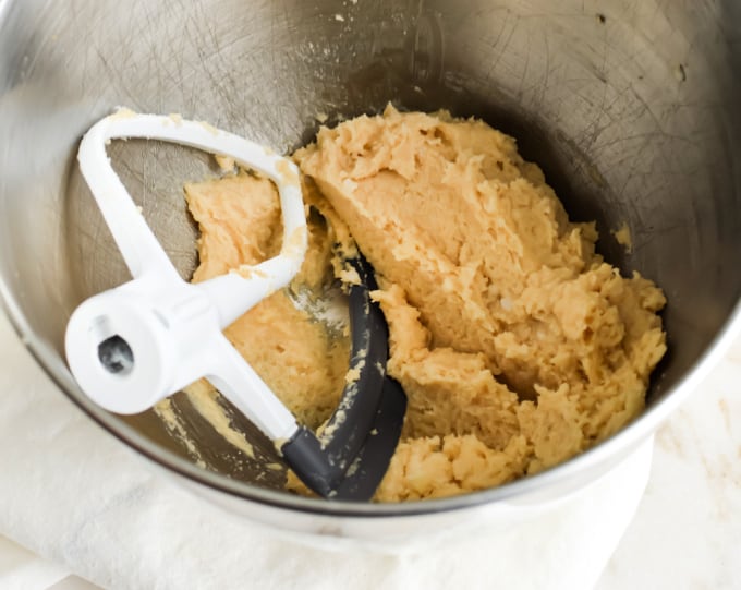 Coconut oil sugar scrub in a stainless steel metal bowl with a beater attachment.