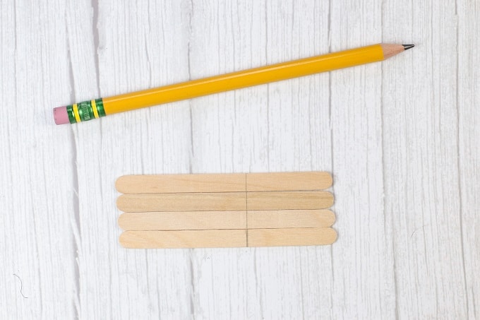 Top down view of a pencil and 4 popsicle sticks.