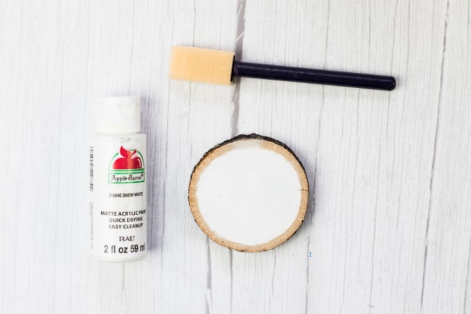 White craft paint, a wood circle painted white and a foam brush.