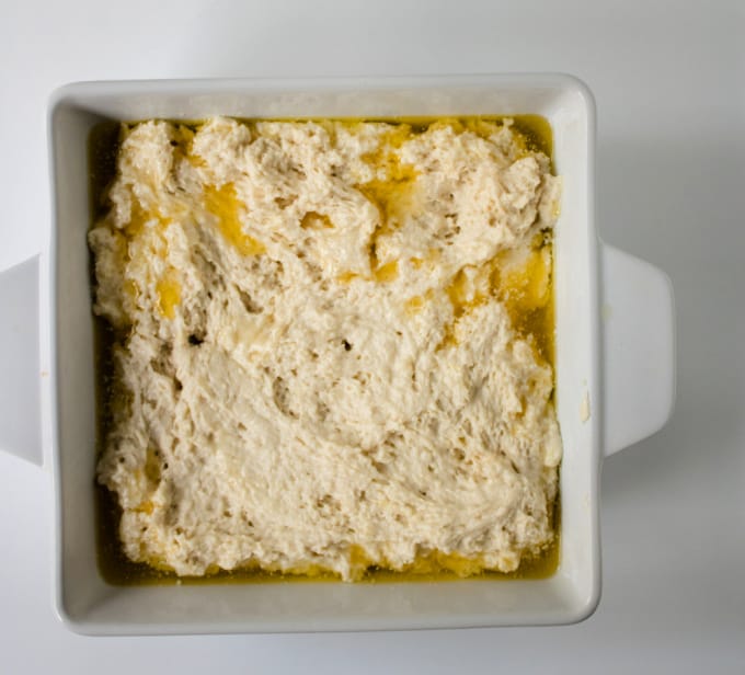 Butter swim biscuit dough in a square baking dish ready to go in the oven.
