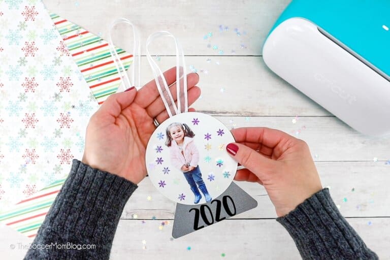 A woman holding a snow globe ornament made with a Cricut cutting machine.