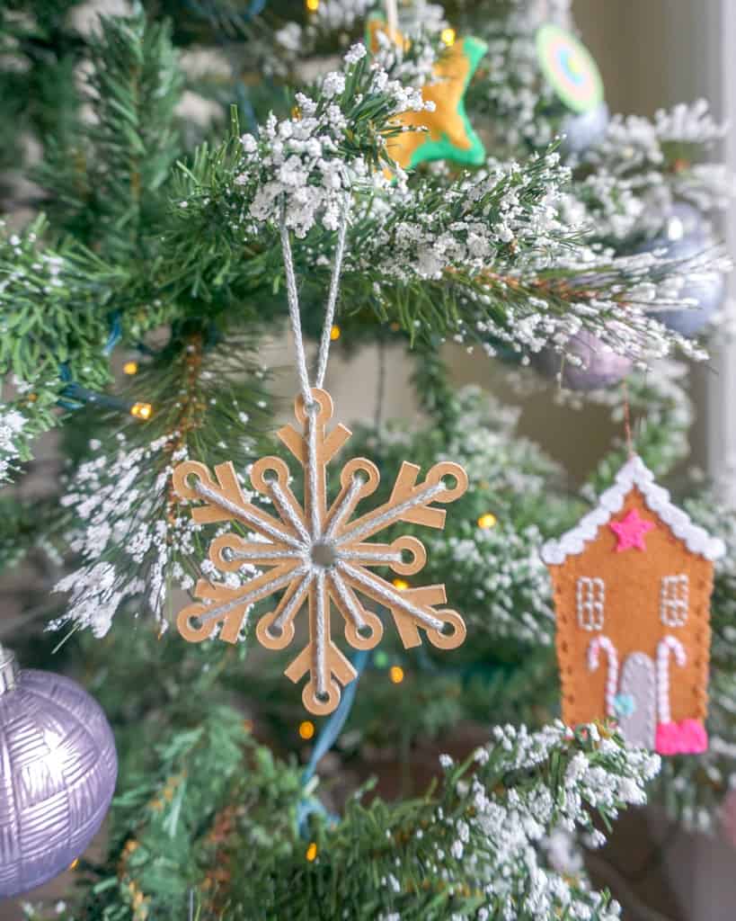 Close up image of a snowflake ornament on a flocked Christmas tree.