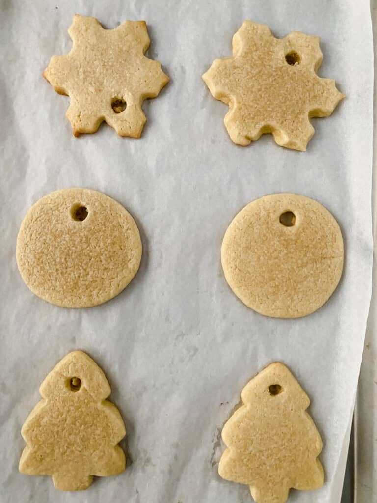 Ornament sugar cookies on a parchment lined baking sheet.