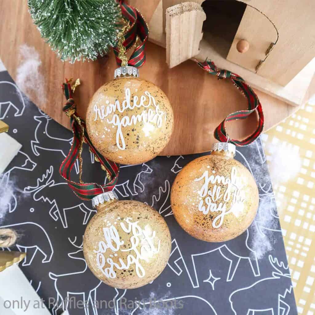 Three DIY glitter ornaments on a festive table top.