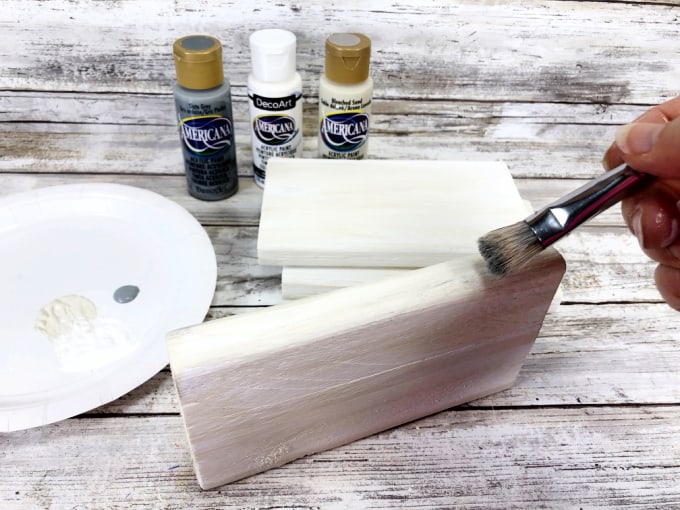 Woman painting wooden blocks.
