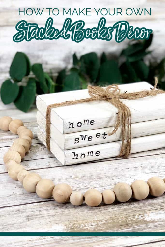 Stacked books decor surrounded by greenery and a wooden garland.