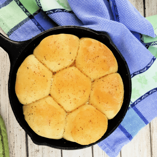 Top down view of buttery dinner rolls in a cast iron skillet.