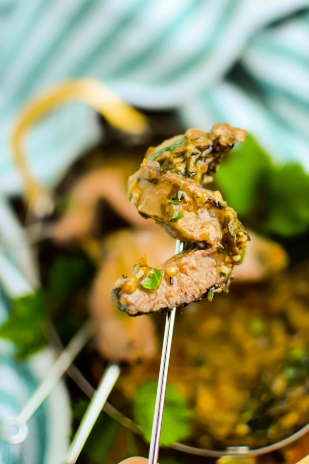 Bite of steak on a skewer covered with garlic butter sauce.