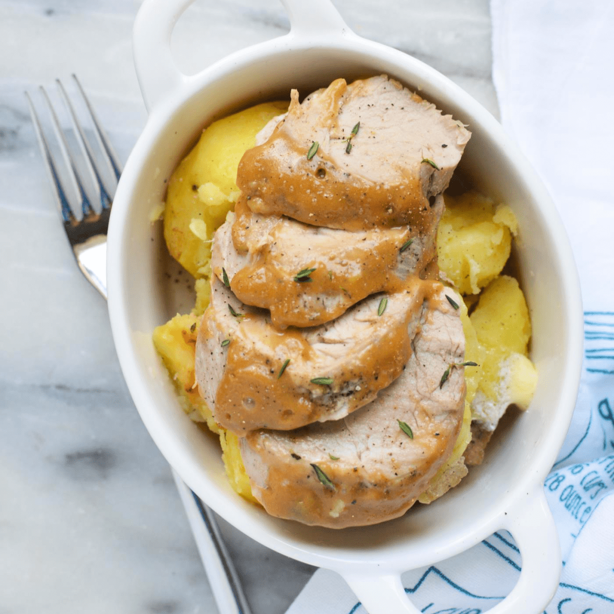 Top down view of Instant Pot Pork Tenderloin and potatoes in a white dish.