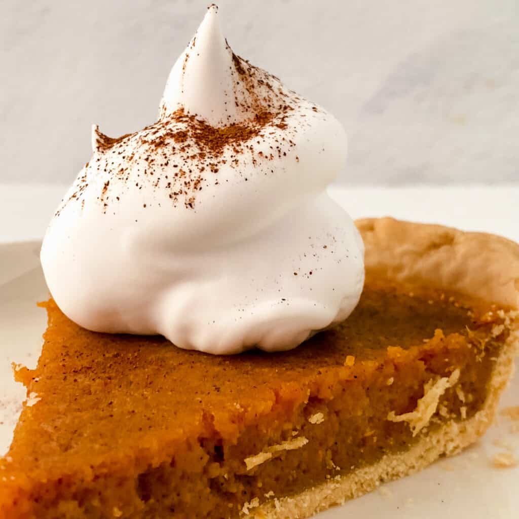 Slice of sweet potato pie with a dollop of whipped cream.