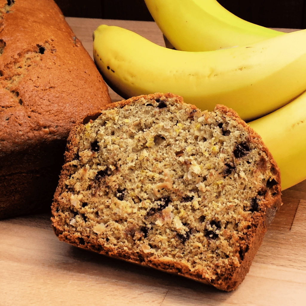 Slice of Banana Coconut Chocolate Chip Bread next to bananas.