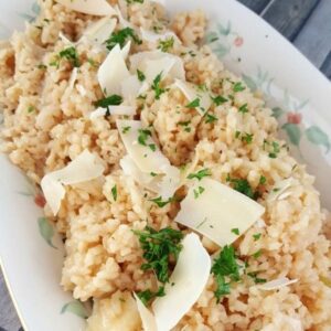 close up of risotto in a serving dish garnished with parmesan and parsley