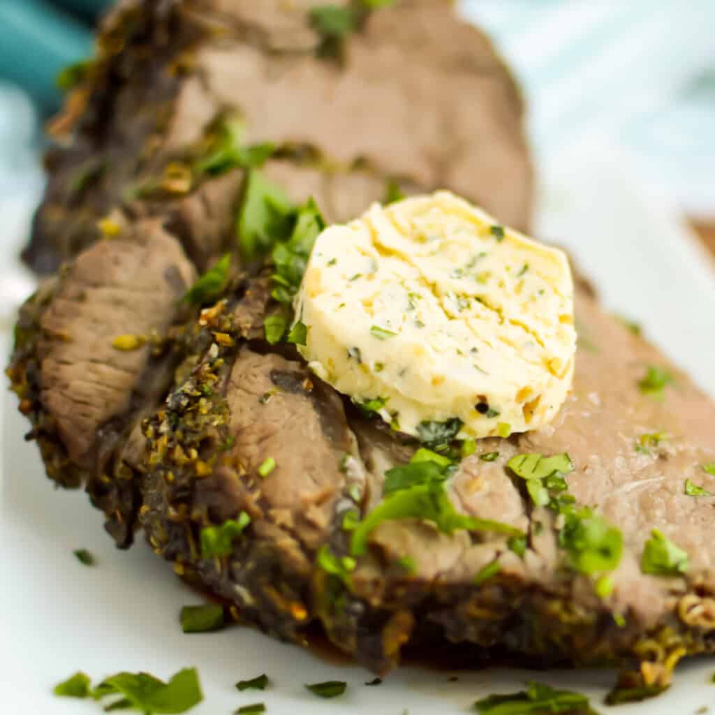 Close up of steak with garlic butter on top.