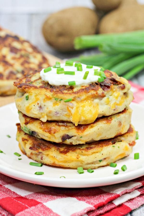 Mashed potato cakes stacked on a white plate.