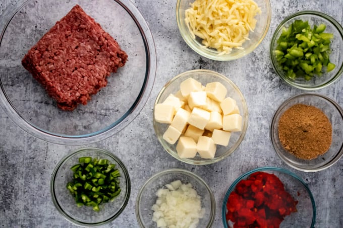 Top down view of ingredients for Beef Queso Dip include onions, peppers and cheeses.