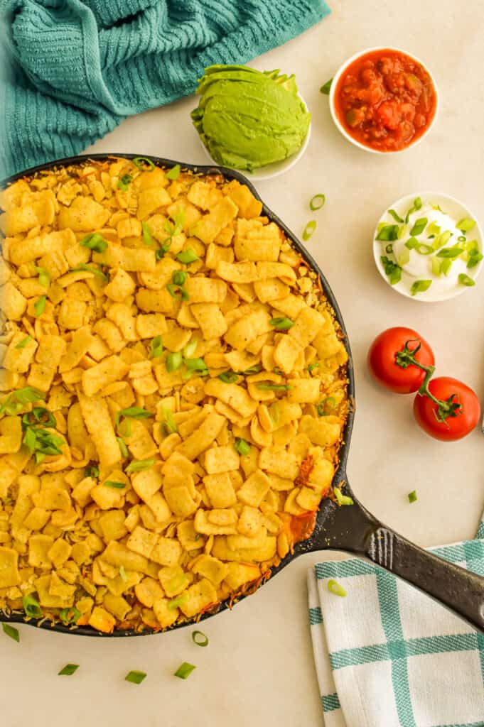 Baked Walking Taco Casserole in a skillet topped with chips.