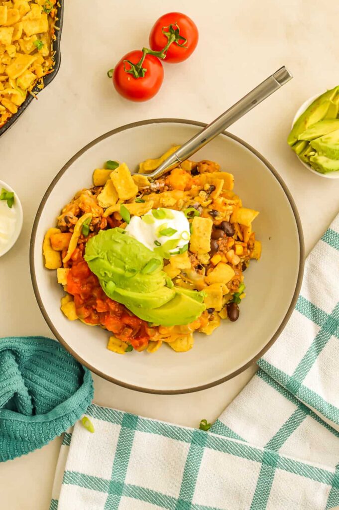 Walking Taco Casserole Recipe in a bowl with sour cream and avocado.
