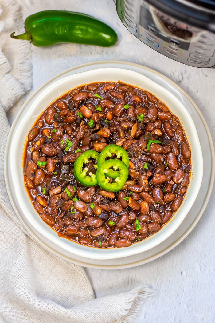 Top down view of Instant Pot Baked Beans in a bowl topped with jalapeno pepper slices.