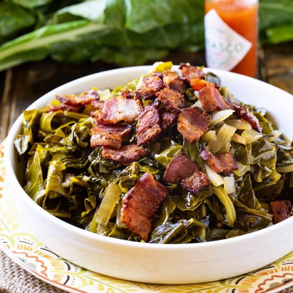 Spcy Collard Greens topped with bacon in a white bowl.
