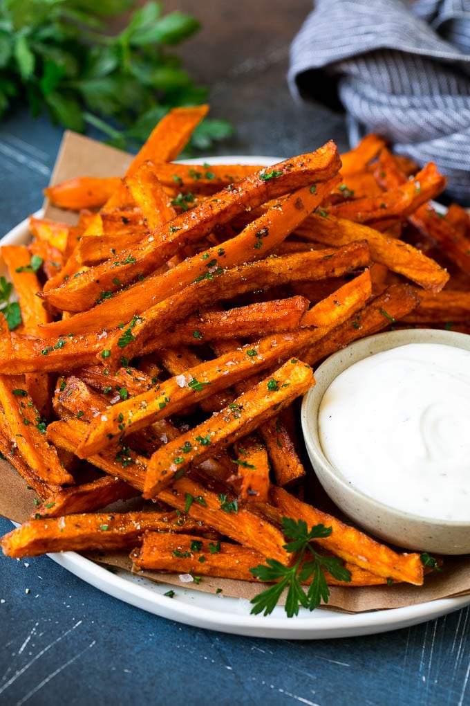 Sweet Potato Fries on a white bowl next to a bowl of dipping sauce.