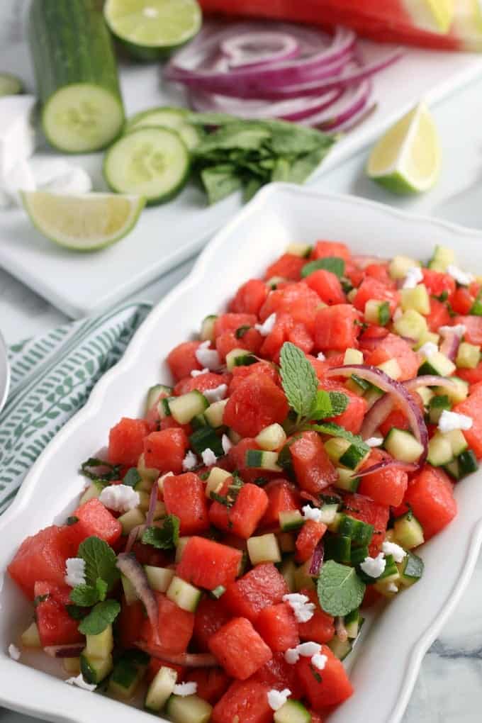 Watermelon salad with cucumber and mint on a rectangular tray.
