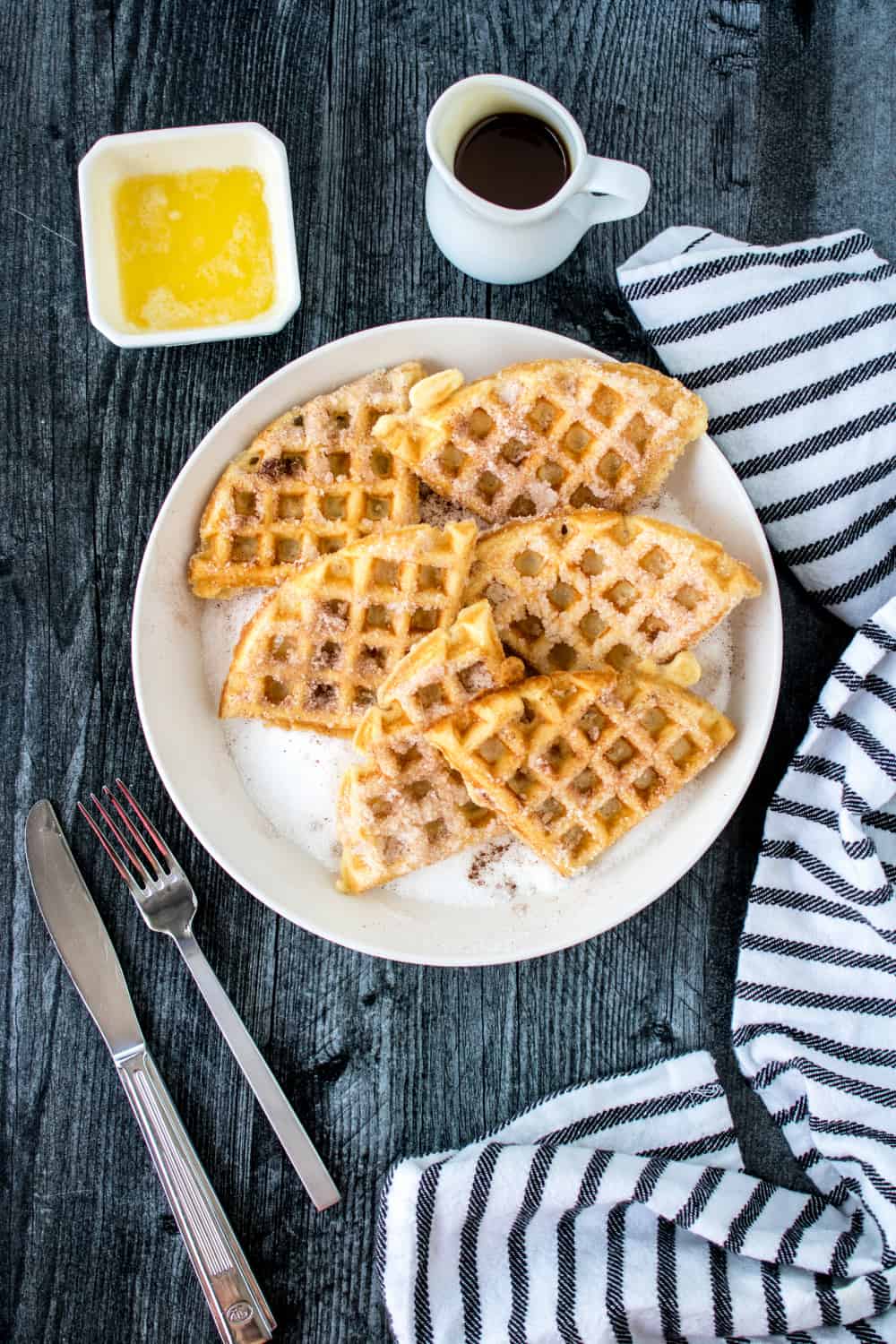 Top down view of Churro Waffles - Cinnamon Sugar Waffles on white plate with butter and maple syrup.