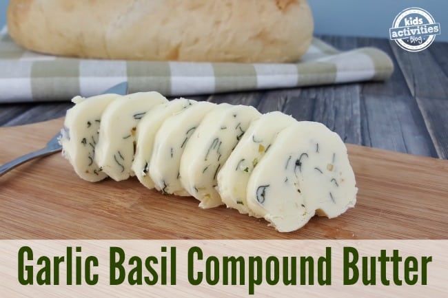 Garlic Basil Compound Butter sliced on a cutting board in front of fresh bread.