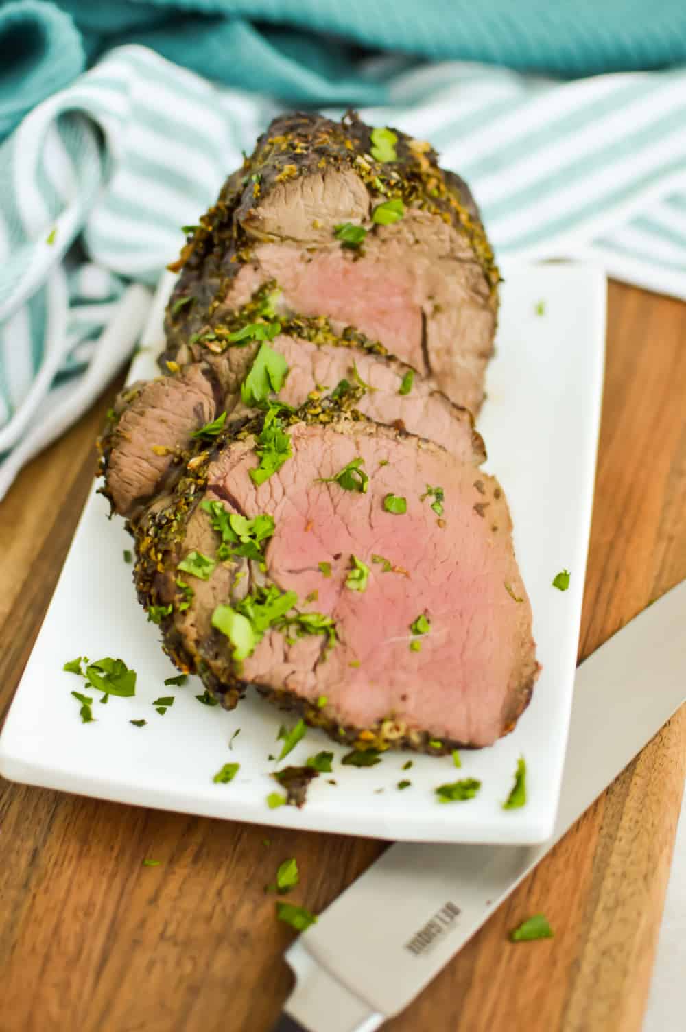 Sliced Petite Sirloin Roast, garnished with parsley, on a white serving platter.