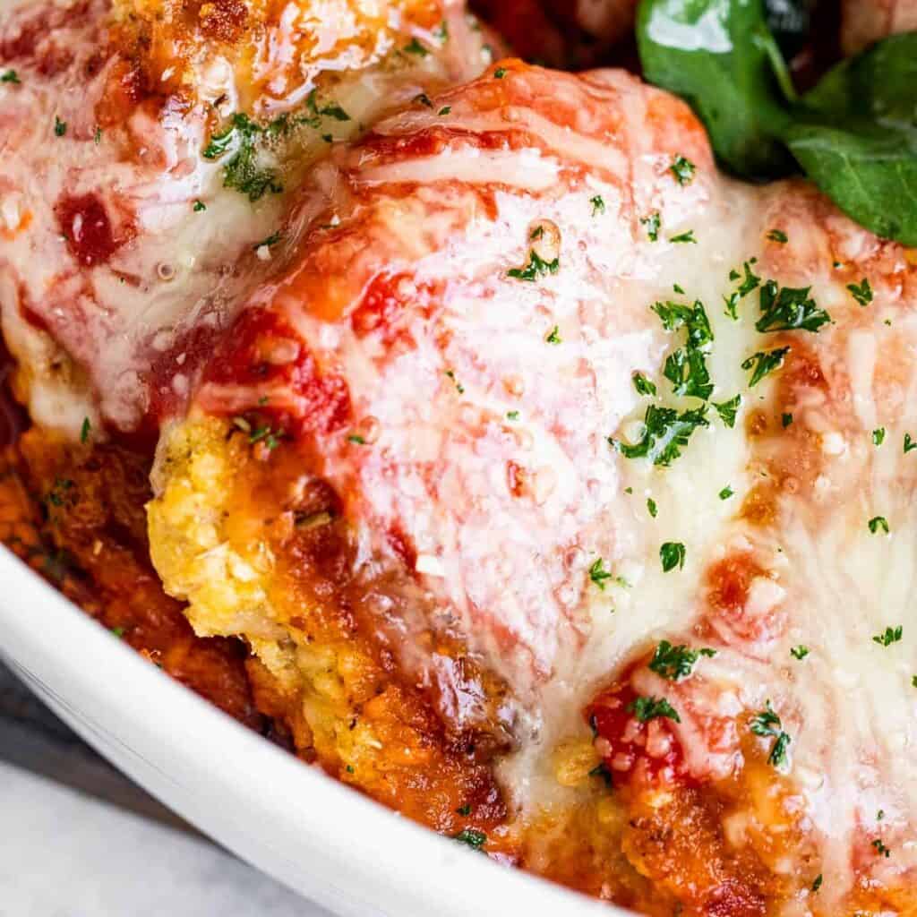 Close up of Pork Parmesan in a white baking dish.